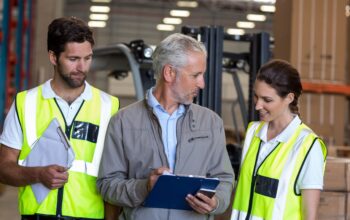 Warehouse manager and workers discussing with clipboard in warehouse