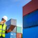 Engineer or a young Asian male foreman Working in the transport of goods using laptops to control the loading of containers at the cargo port for the foreman of the import of export goods.
